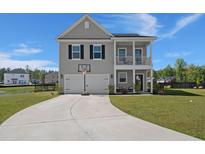 Charming two-story home with a front porch, two-car garage, basketball hoop, and a well-manicured lawn at 118 Jesup Ct, Ridgeville, SC 29472