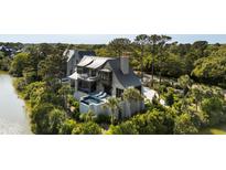 Stunning multilevel home featuring a private pool, balcony, and serene water views surrounded by lush greenery at 20 Old Cedar Ln, Kiawah Island, SC 29455