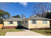 Charming ranch-style home featuring a well-manicured lawn, light yellow siding, and inviting blue shutters at 1120 Seaside Ln, Charleston, SC 29412