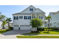 Charming two-story white home boasts a three-car garage, manicured lawn and classic design elements at 1562 Charming Nancy Rd, Charleston, SC 29412