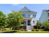 Charming two-story home with light blue siding, white trim, front porch and well-manicured front lawn and decorative landscaping at 1659 Pierce St, Daniel Island, SC 29492