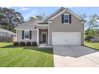 Charming single-Gathering home showcasing a well-manicured lawn and two-car garage at 171 Sara St, Saint George, SC 29477