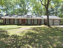 Charming brick ranch home with a well-manicured lawn and mature trees at 1527 S Pinebark Ln, Charleston, SC 29407