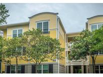 Lovely yellow condominium building with well-maintained landscaping, featuring mature trees at 1832 Telfair Way # 1832, Charleston, SC 29412
