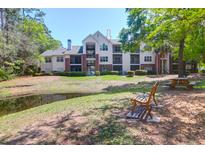 Apartment building with well-maintained landscaping and pond view from shaded bench seating area at 2011 N Highway 17 # 1400T, Mount Pleasant, SC 29466