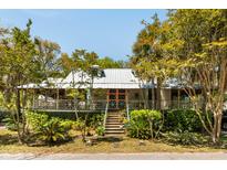 Charming home features a metal roof, colorful entrance, landscaped yard, and covered front porch at 2808 Ion Ave, Sullivans Island, SC 29482