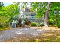 Charming home featuring a covered porch and landscaped yard with a mature tree and a gravel driveway at 281 Hawthorne St, Mount Pleasant, SC 29464