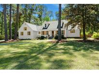 Charming white home with shuttered windows sits on a lush green lawn beneath mature shade trees at 309 Huntington Rd, Summerville, SC 29483