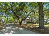 Stately home nestled among mature trees, featuring a long driveway and multiple garage spaces at 5569 Frisco Ln, Johns Island, SC 29455