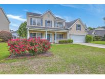 Charming two-story home featuring a well-manicured lawn and a beautiful flower bed at 9379 Harroway Rd, Summerville, SC 29485