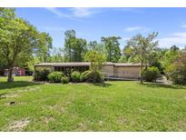 Inviting single-story home featuring a lush green lawn and mature trees under a clear blue sky at 1019 Levi Lake Rd, Johns Island, SC 29455