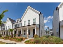 Charming two-story home featuring a covered front porch with brick accents, and landscaped yard at 119 Summer Tanager Dr, Ravenel, SC 29470