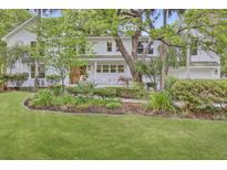 Charming two-story home with a lush green lawn, manicured landscaping, and a welcoming front porch at 126 Sparrow Dr, Isle of Palms, SC 29451