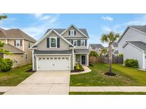 Charming two-story home features a well-manicured lawn and attached two-car garage with neutral siding and a palm tree at 1426 Tannery Row, Johns Island, SC 29455