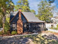 Quaint home with a brick chimney, screened porch, and mature trees in a landscaped yard at 1456 Remount Rd, North Charleston, SC 29406