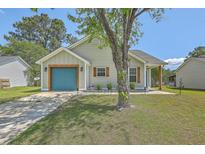 Charming home featuring a well-manicured lawn, a light-green facade, and a vibrant blue garage door at 203 Two Hitch Rd, Goose Creek, SC 29445