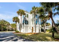 Stunning modern home showcasing its clean lines, surrounded by lush palm trees and a well-manicured lawn at 23 Fairway Village Ln, Isle of Palms, SC 29451