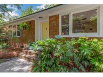 Charming brick home featuring a bright yellow front door and lush greenery around the entrance at 1172 Dawn Dr, Charleston, SC 29412