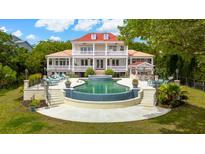 An extravagant two-story home boasts a stunning backyard pool with lounge chairs and a bar area for outdoor entertaining at 13 Broughton Rd, Charleston, SC 29407