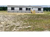 Charming single-story home with gray siding, a covered front porch, and a spacious yard at 1358 Givhans Rd, Ridgeville, SC 29472