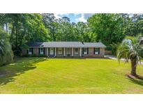Charming brick home featuring a manicured lawn and inviting curb appeal with mature trees and a classic design at 1621 Wannamaker Ave, Summerville, SC 29485
