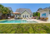 Inviting backyard with a sparkling pool, lush lawn, and comfortable lounge area at 2009 Terrabrook Ln, Charleston, SC 29412
