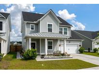 Charming two-story home with a well-manicured lawn, metal roof, and a welcoming front porch at 206 Evergreen Ave, Summerville, SC 29485