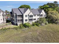 Condo building with a dark gray roof with screened in porches on each floor overlooking grassy waterfront at 2134 Landfall Way, Seabrook Island, SC 29455