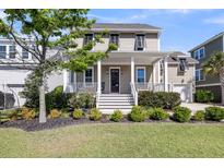 Charming two-story home featuring a welcoming front porch, manicured lawn, and mature landscaping at 2636 Colonel Harrison Dr, Johns Island, SC 29455
