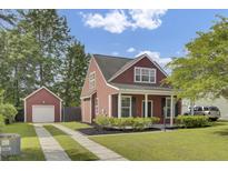 Charming red two-story home with a manicured lawn, complemented by a detached garage and inviting curb appeal at 4856 Cane Pole Ln, Summerville, SC 29485