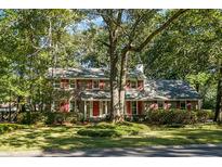 Charming two-story brick home with mature trees and red shutters on a sunny day at 112 Huckleberry Ln, Summerville, SC 29485