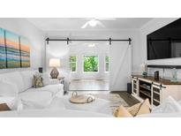 Bright living room with white furniture, barn door to office, and light-filled windows at 1984 Folly Rd # B114, Charleston, SC 29412