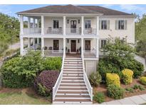 Beautiful two-story home featuring double porches, white railings, and a meticulously landscaped front yard at 2269 Hartfords Bluff Cir, Mount Pleasant, SC 29466