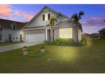 Charming single-Gathering home boasts a well-manicured lawn and features a mix of brick and siding at dusk at 349 Long Pier St, Summerville, SC 29486