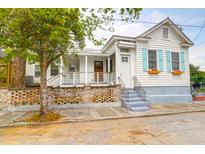 Charming exterior featuring white siding, light blue shutters and a brick wall around the raised front yard at 4 Addison St, Charleston, SC 29403