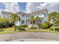Inviting two-story home with white siding, a front porch, palm trees, and lush landscaping, offering classic curb appeal at 509 Gilberts Lndg, Mount Pleasant, SC 29464