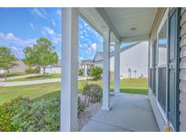 Inviting covered front porch with white columns and views of the well-maintained front yard and landscaping at 7477 Painted Bunting Way, Hanahan, SC 29410