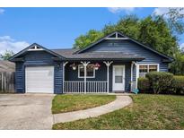 Charming blue home with a white porch, green lawn, and attached garage at 8268 Timberidge Ct, North Charleston, SC 29420