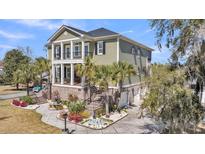 Stunning three-story home featuring a beautifully landscaped front yard and a classic exterior with elegant architectural details at 1305 Old Rice Mill Rd, Moncks Corner, SC 29461