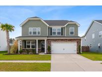 Inviting two-story home with a landscaped front yard, charming brick accents, and an attached two-car garage at 205 Honey Horn Dr, Summerville, SC 29486