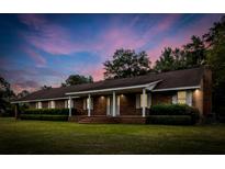 Charming brick home with a long covered porch and manicured landscaping at 228 Dogwood Trl, Harleyville, SC 29448