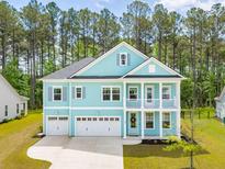 Inviting two-story home with a three-car garage, double balconies and light-blue siding at 307 Theus Pl, Huger, SC 29450