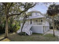 Charming raised beach house featuring a metal roof, classic white railings, and beautiful natural surroundings at 3320 Myrtle St, Edisto Island, SC 29438