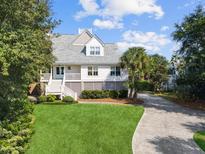 Inviting exterior showcasing a well-manicured lawn and classic staircase leading to the covered front porch at 6 Intracoastal Ct, Isle of Palms, SC 29451