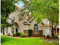 Charming two-story home with tan siding, brick accents, manicured lawn and mature landscaping provides great curb appeal at 8624 Grassy Oak Trl, North Charleston, SC 29420
