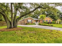 Charming brick home featuring a well-maintained lawn, mature trees, and a welcoming entrance at 902 Mikell Dr, Charleston, SC 29412