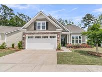 Charming single-story home with a two-car garage, stone accents, manicured lawn, and a welcoming front porch at 1011 Old Field Dr, Summerville, SC 29483