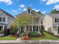 Charming two-story home with a welcoming front porch and balcony, surrounded by lush landscaping and mature trees at 1753 Bee Balm Rd, Johns Island, SC 29455