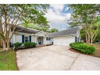 Charming one-story home features a large driveway, attached garage, light gray siding, and well-manicured landscaping at 1922 Cedar Petal Ln, Charleston, SC 29414