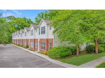 Townhome with cream siding and red brick bottom, surrounded by lush trees and landscaping at 241 Howle Ave # H, Charleston, SC 29412